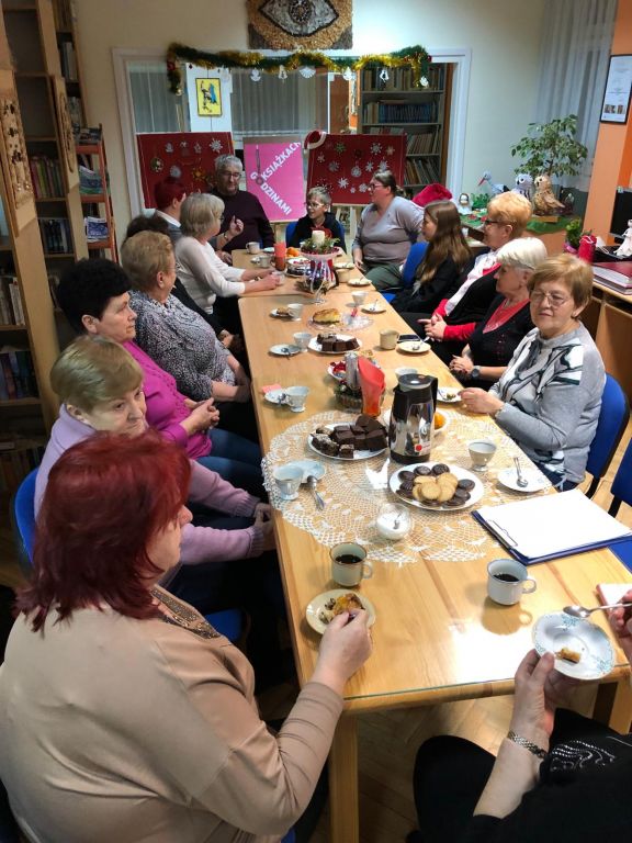 Uczestnicy spotkania Dyskusyjnego Klubu Książki siedzą przy stole i rozmawiają