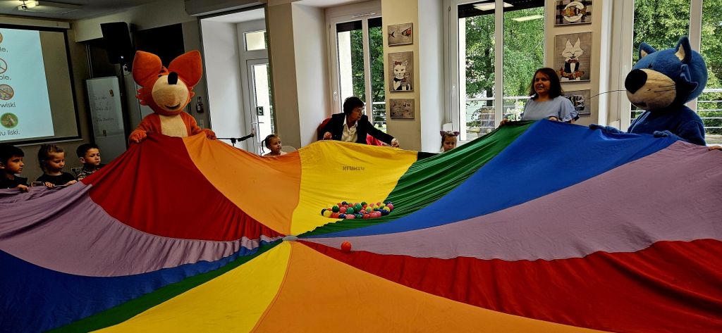 Dzieci wraz Fenkiem i Maksiem bawią się kolorową chustą Klanzy