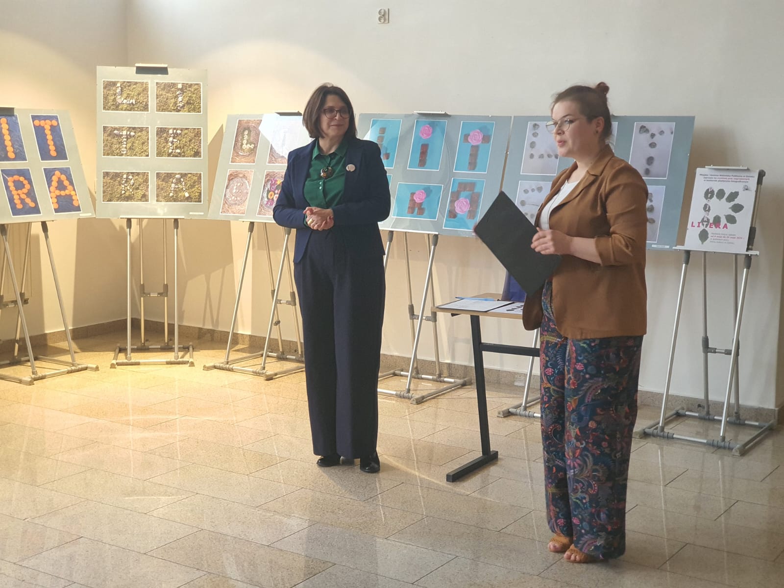 Bibliotekarka odpowiedzialna za przeprowadzenie konkursu stoi przed widzami i omawia gł&oacute;wne kryteria oceny jury.