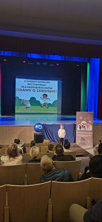 Dziewczynka stoi na podeście i recytuje wiersz