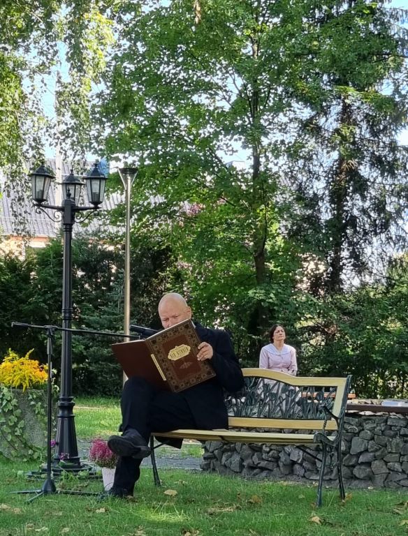 Mężczyzna siedzi na ławce w parku i czyta książkę