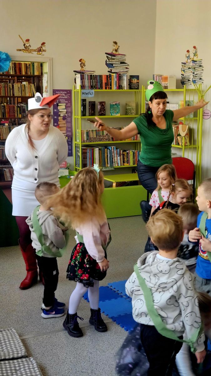 Bibliotekarki przebrane za żabę i bociana prowadzą zabawę z dziećmi