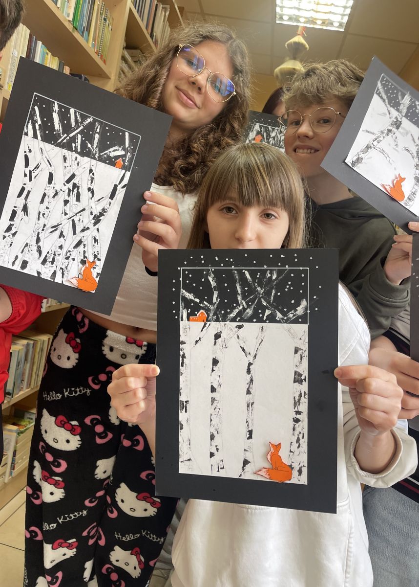 Troje dzieci pokazuje swoje prace.