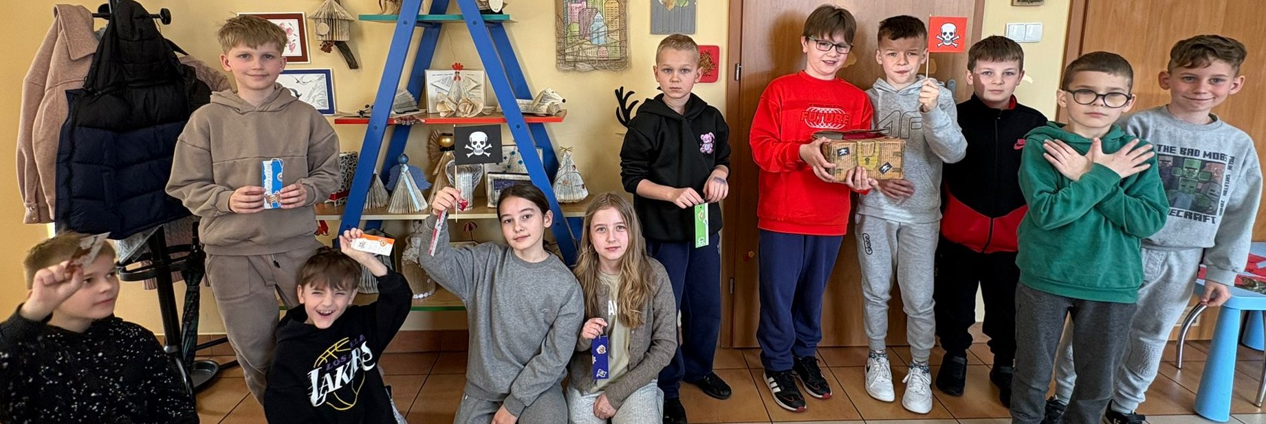Cała klasa pozuje do zdjęcia. Kapitan zwycięskiej drużyny  prezentuje zdobytą skrzynkę skarb&oacute;w.