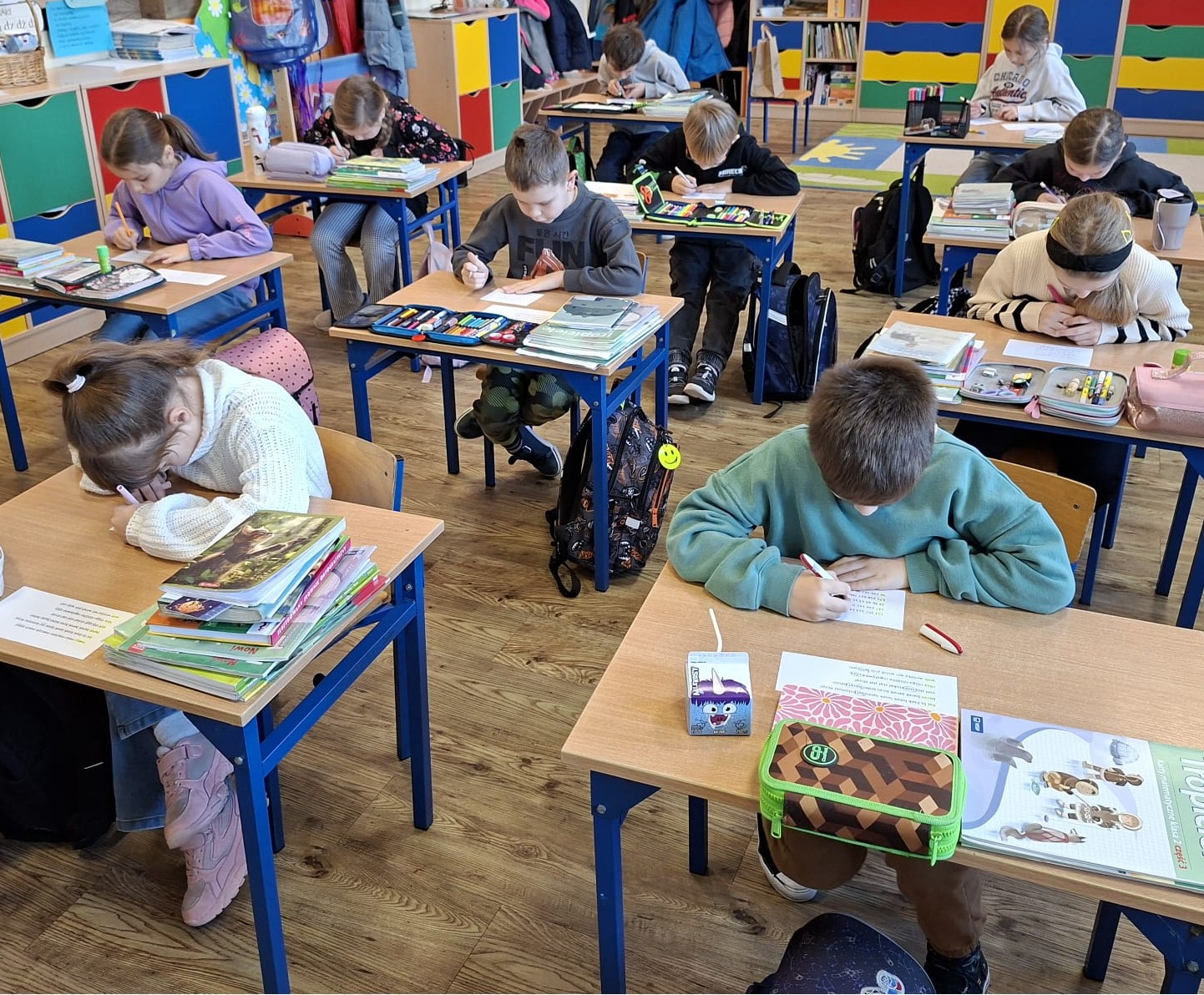 dzieci siedzą w ławkach i wykonują zadanie