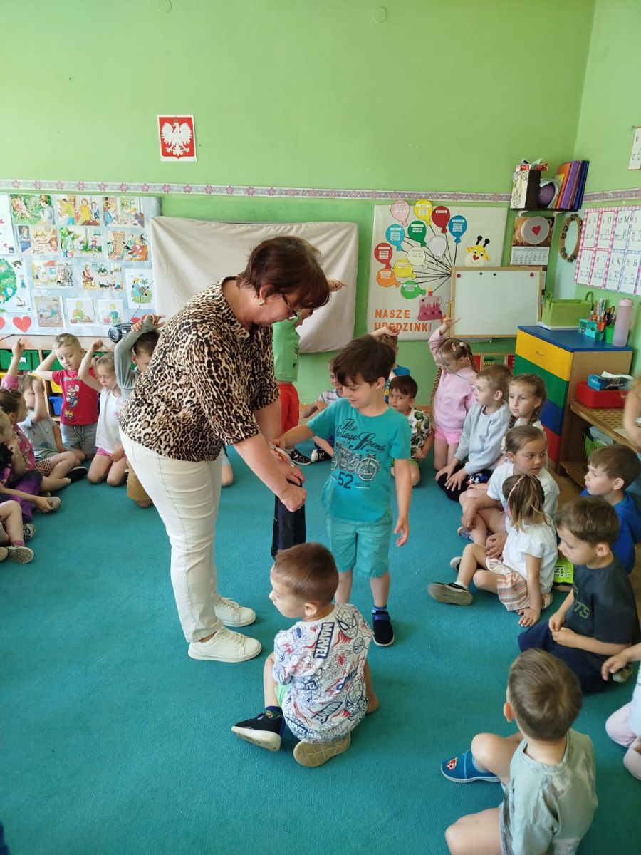 Chłopczyk losuje z czarnego worka przedmiot. Worek trzyma bibliotekarka.