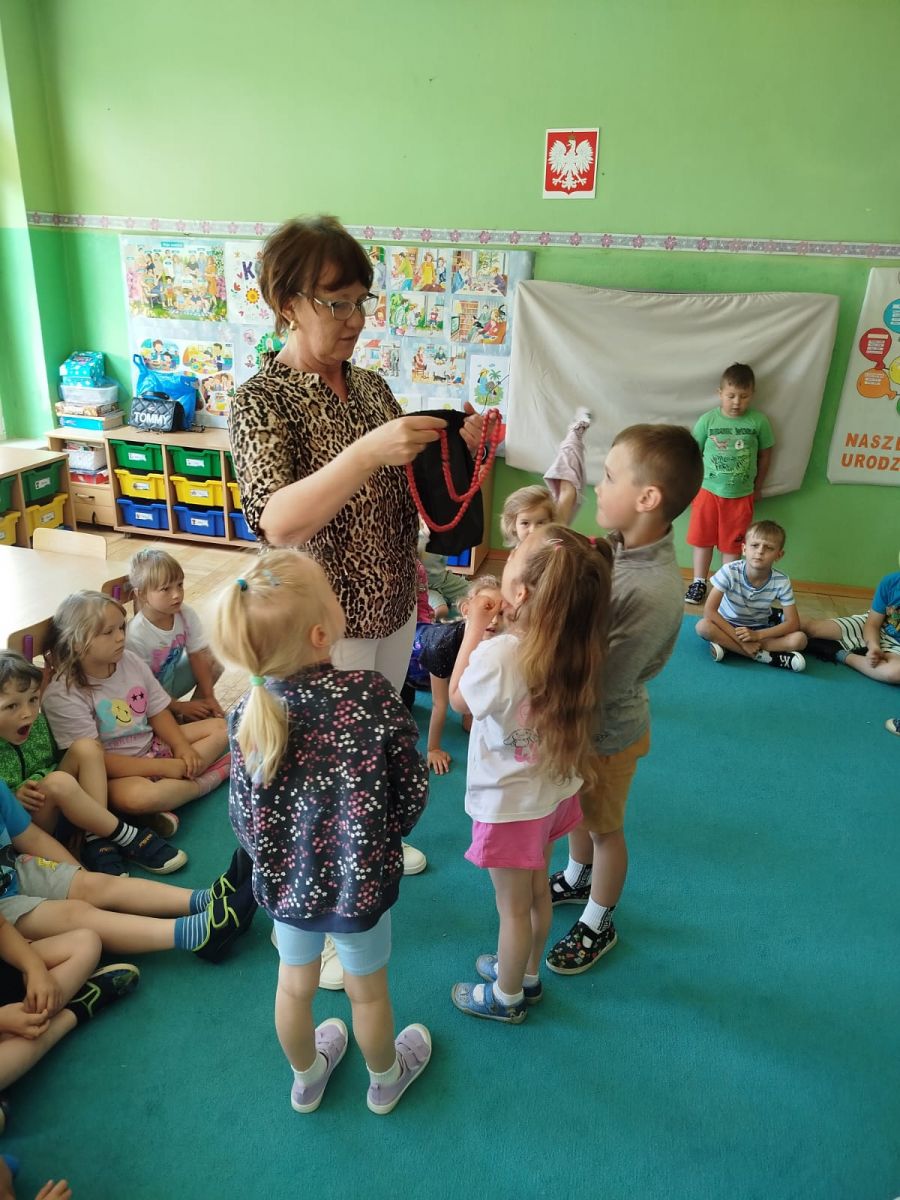 Pani bibliotekarka pokazuje dzieciom czerwone korale.