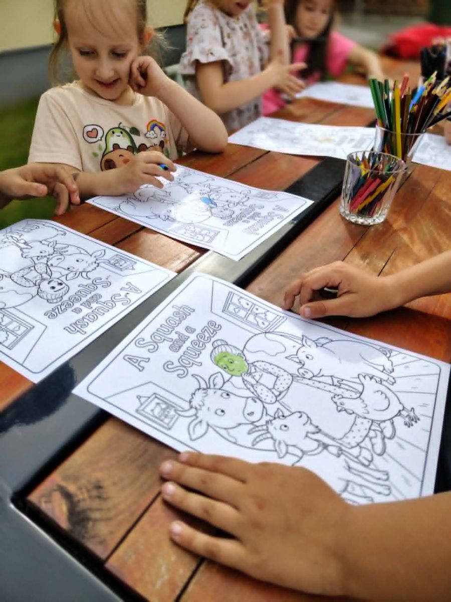 dzieci kolorują kolorowankę na stole