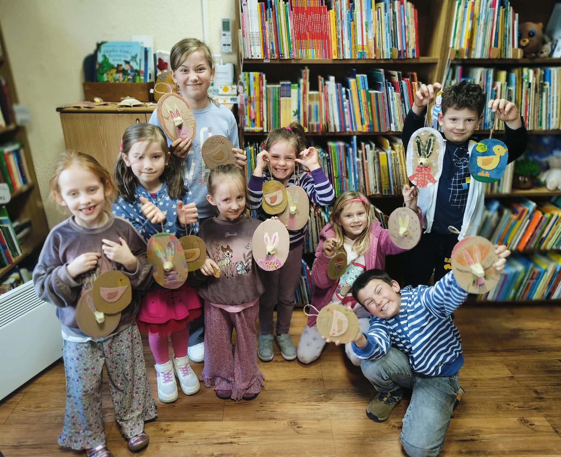 Dzieci stoją w grupie i prezentują wykonane prace plastyczne.