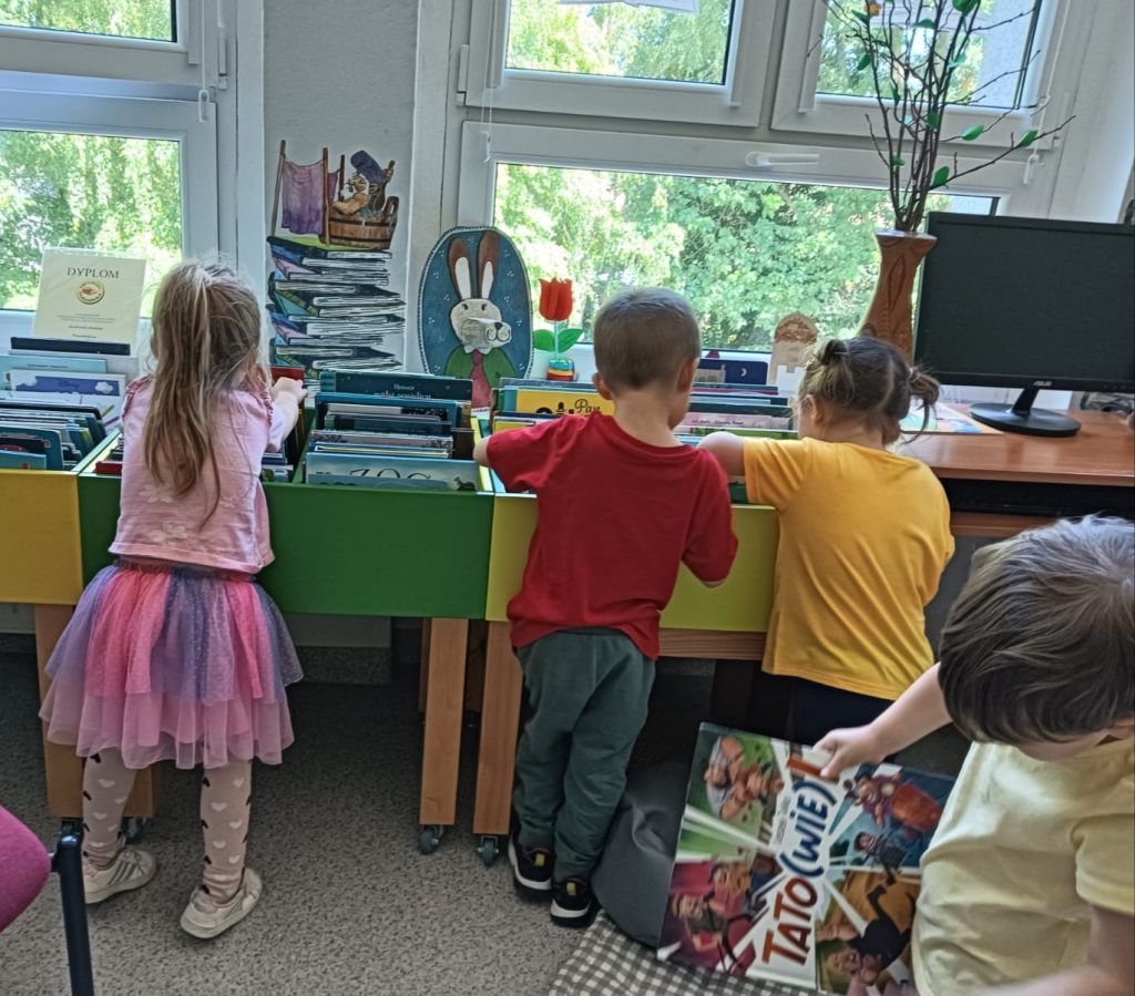 Dzieci przeglądają biblioteczne książeczki
