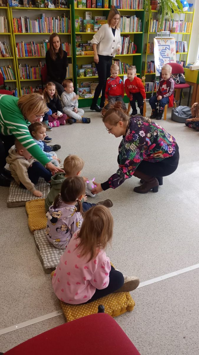 Prowadząca zajęcia oraz dziecko pochylają się nad robotem edukacyjnym, kt&oacute;ry w tym czasie zmienia kolor świecących się na jego głowie czułek.