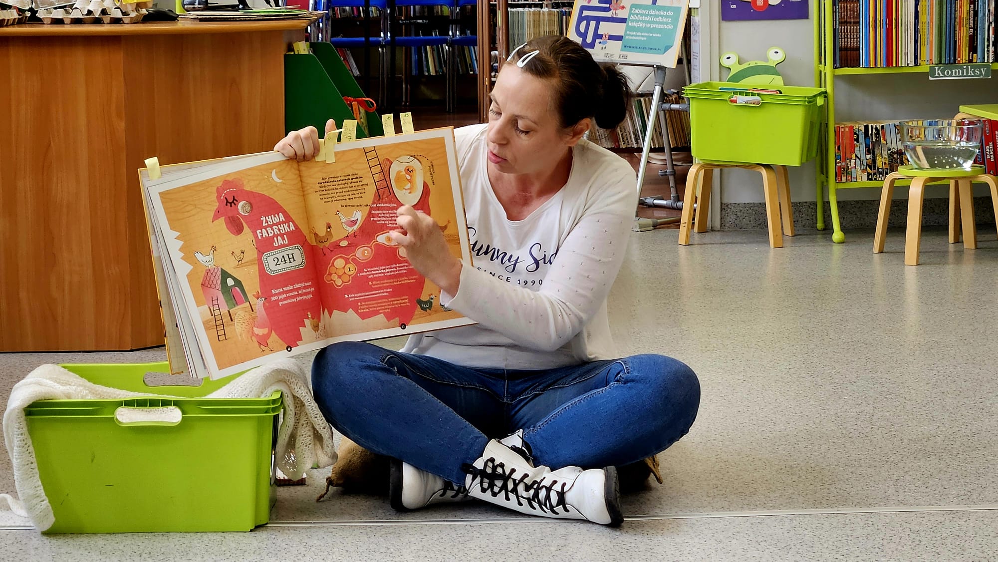 Bibliotekarka pokazuje ilustracje o powstawaniu jajka w książce.