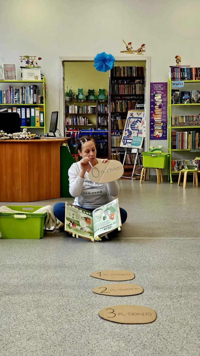 Bibliotekarka pokazuje i tłumaczy dzieciom specjalny kod umieszczany na skorupkach jaj.