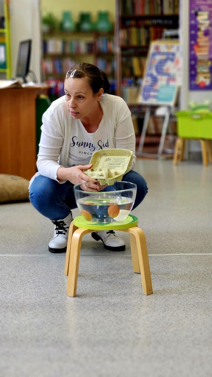 Bibliotekarka uczy dzieci poprzez doświadczenie z wodą jak ropoznać świeże jajko od starego.