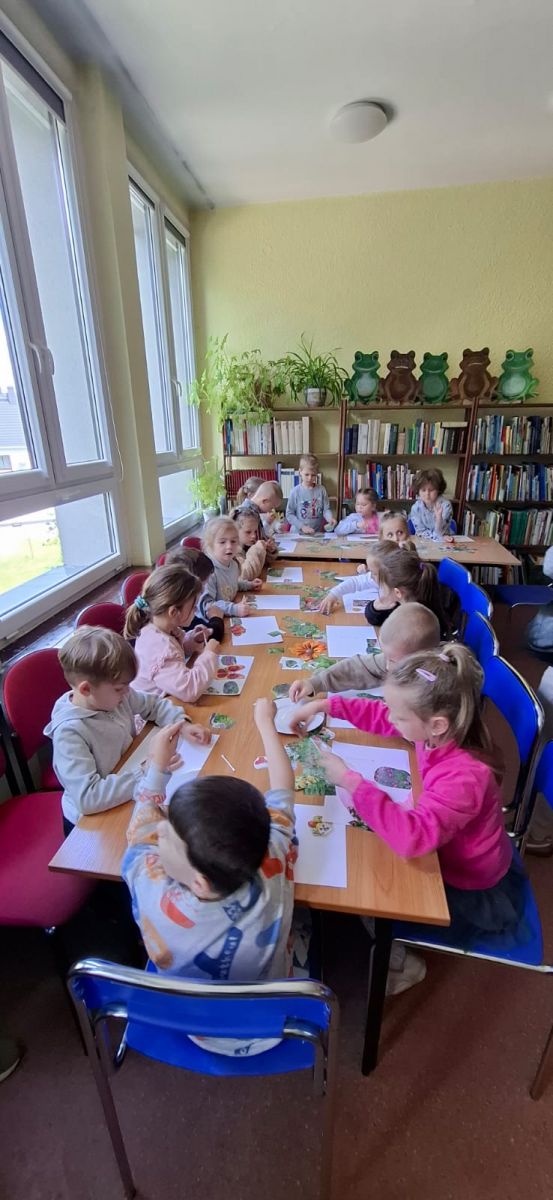 Dzieci siedzą przy stole i wykonują parce plastyczne.