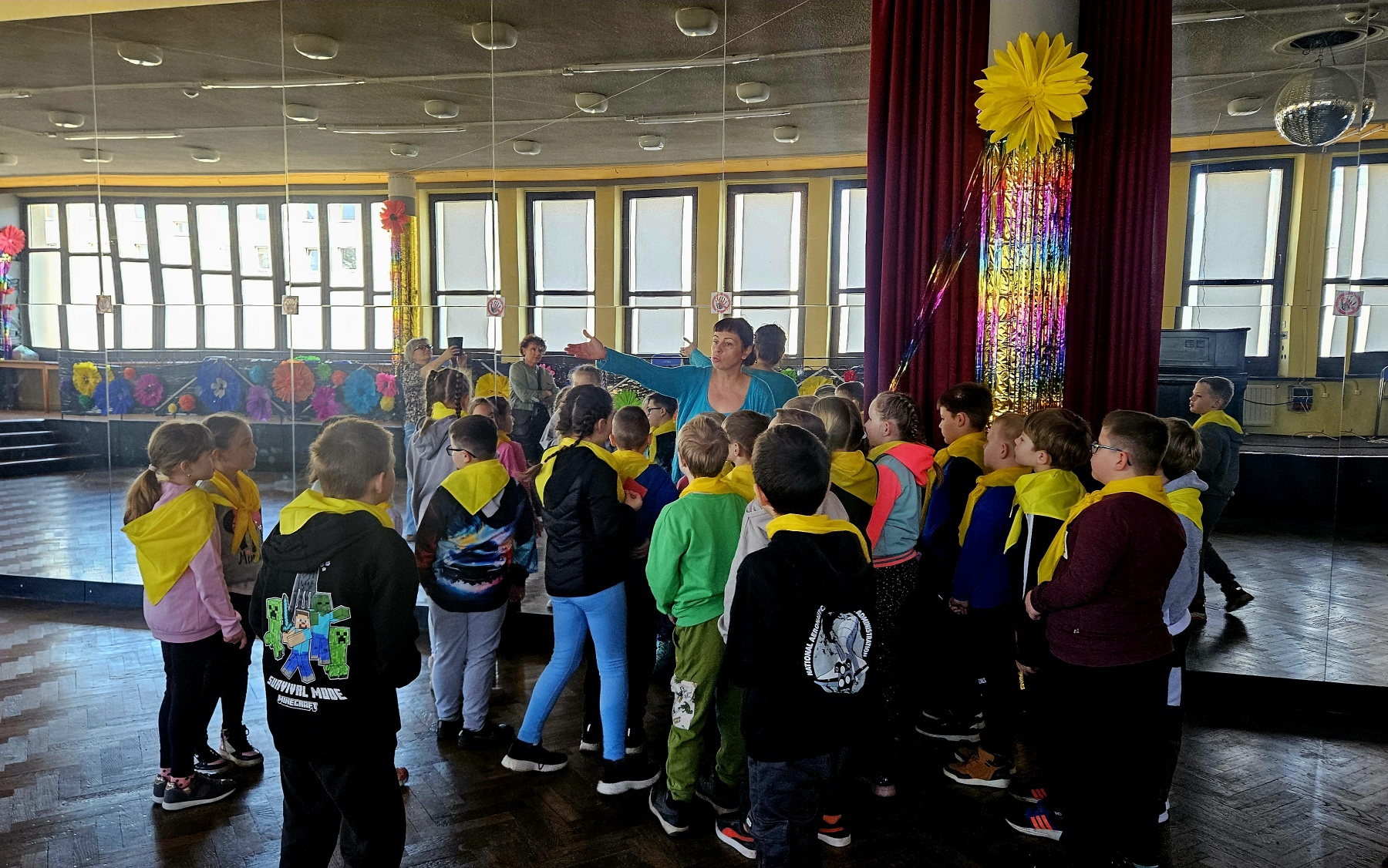 Grupa dzieci przygotowuje się do wsp&oacute;lnego tańca pod kierunkiem bibliotekarki