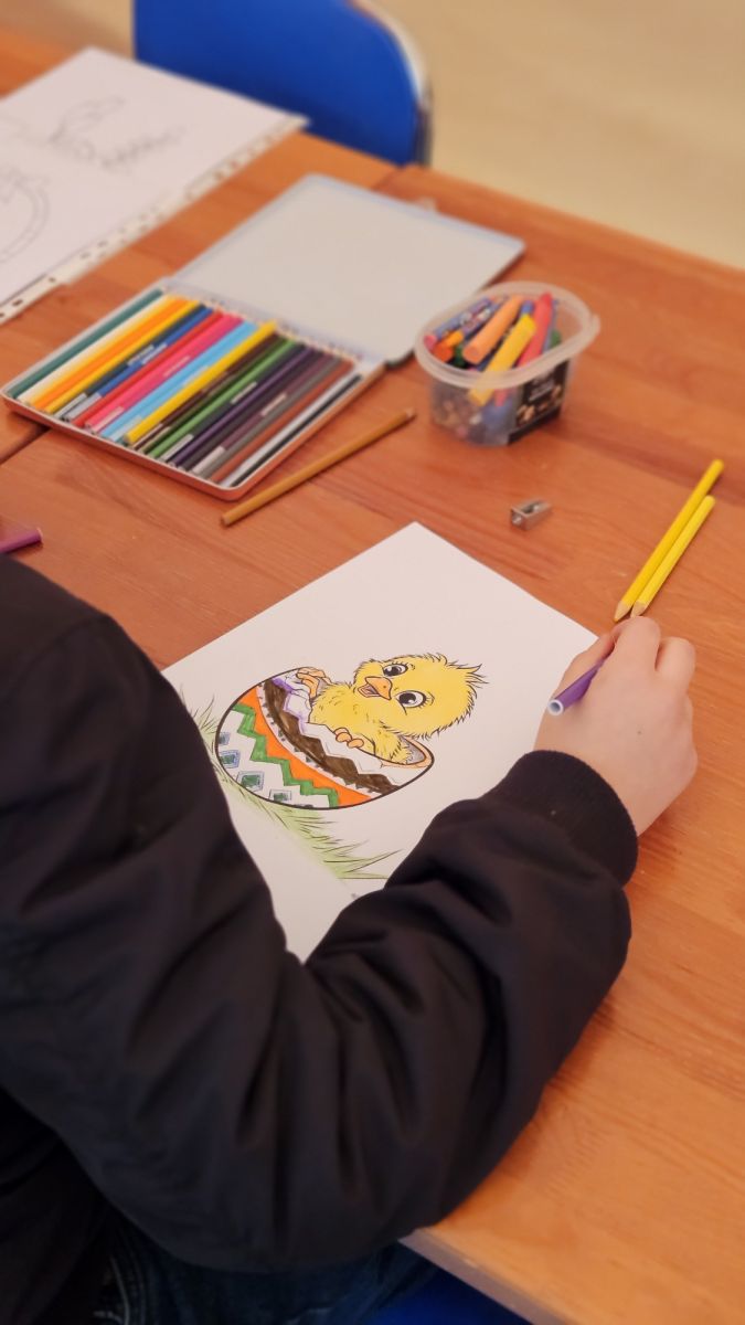 Dziecko koloruje świąteczny obrazek z kurczakiem