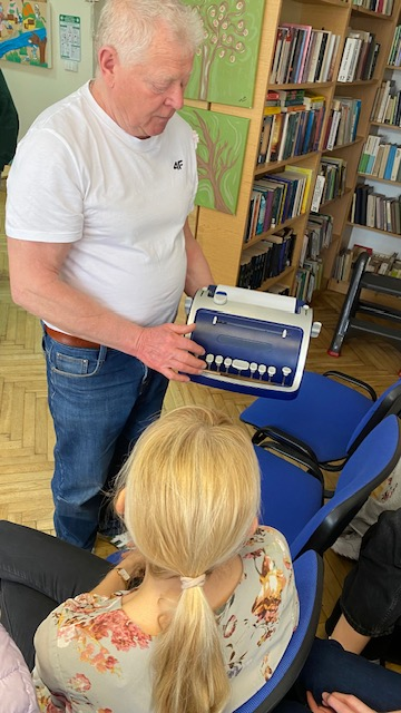 Mężczyzna pokazuje maszynę do pisania alfabetem Braille'a