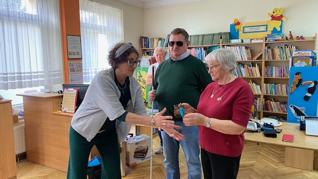 Kobieta pokazuje jak działa urządzenie do sygnalizowania poziomu wody w szklance