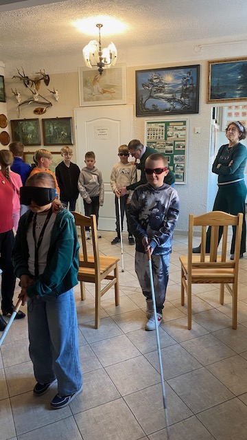 Uczniowie z zasłoniętymi oczami pr&oacute;bują samodzielnie przejść tor przeszk&oacute;d z białą laską 