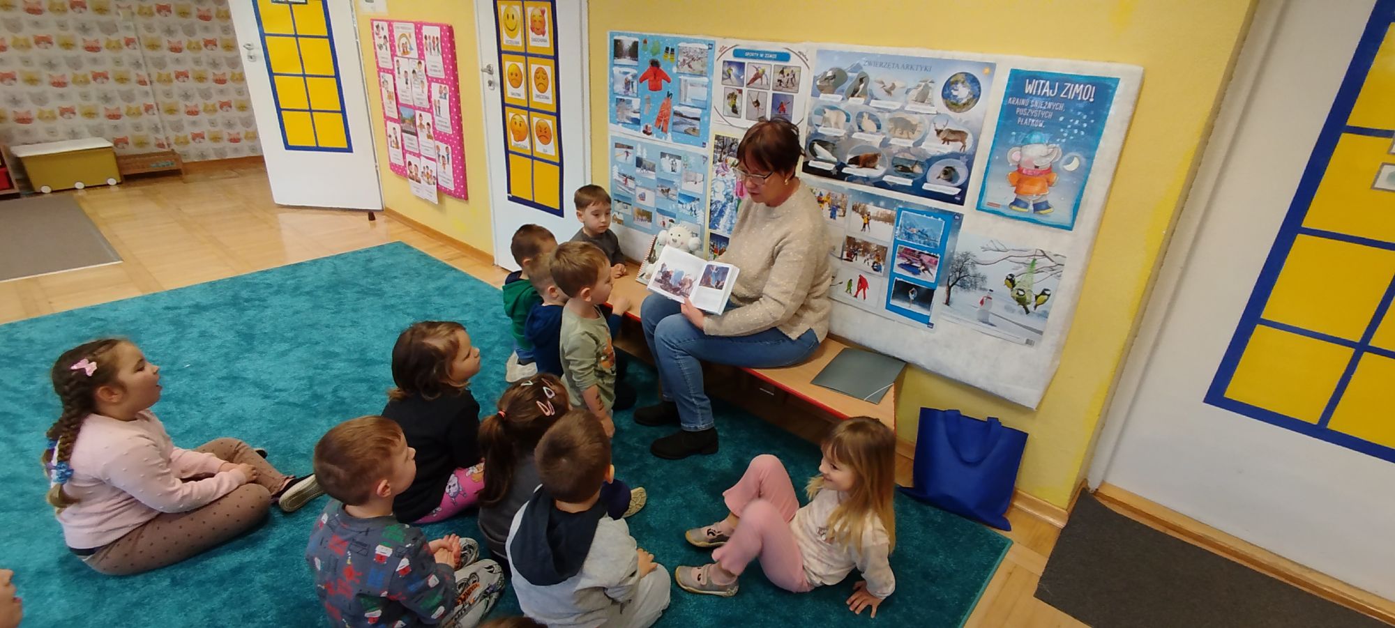 Pani pokazuje dzieciom ilustracje z książki "Kraina Lodu"