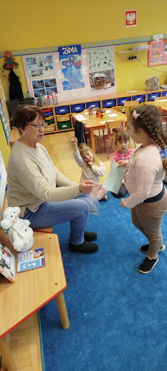 Dziewczynka losuje zimowy szablon potrzebny do wykonania mini zabawy ruchowej.